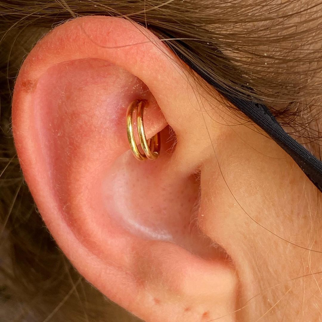 Dubbele oorpiercing met gouden hoepels