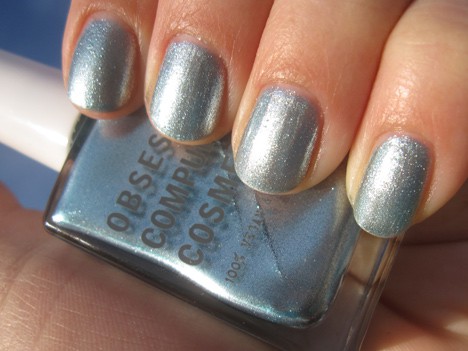 Een hand met een pastel zilverachtig blauw met een ondoorzichtige/metallic afwerking nagellak met een nagellak van dezelfde kleur