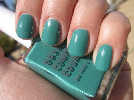 Een hand met een levendig blauwgroen met een ondoorzichtige/satijnen nagellak met een nagellak van dezelfde kleur