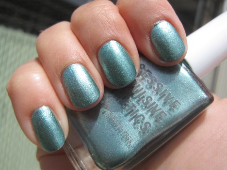 Een hand met een metallic blauwgroen met een ondoorzichtige/metallic afwerking nagellak met een nagellak van dezelfde kleur