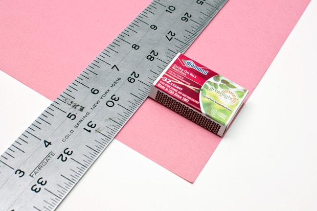 Een liniaal, luciferdoosje en roze papier 