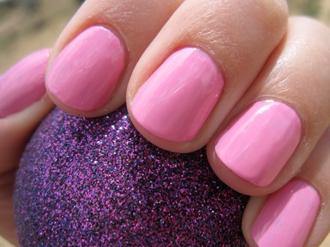 Een hand met een roze nagellak die een paarse met glitters bal vasthoudt