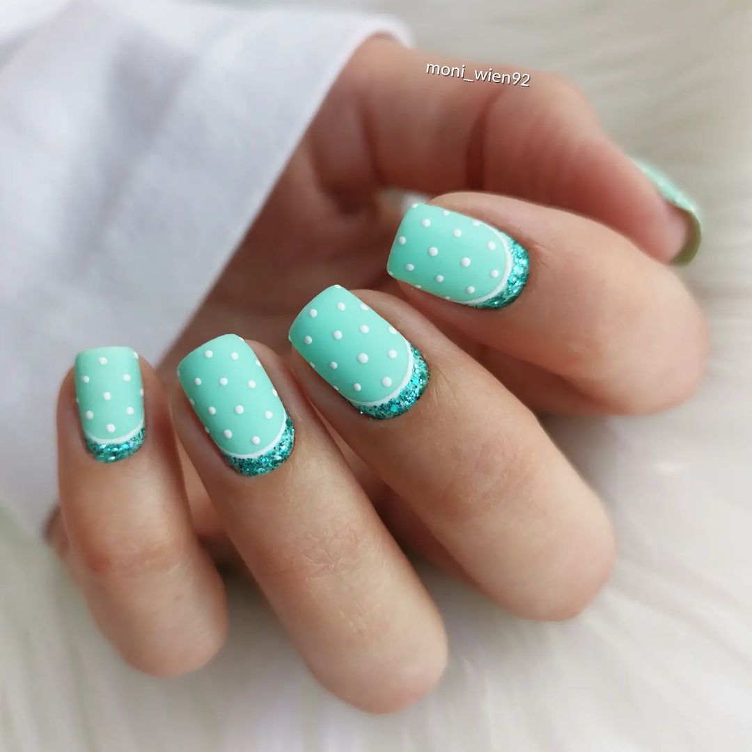 Korte lichtgroene nagels met glitter en witte stippen
