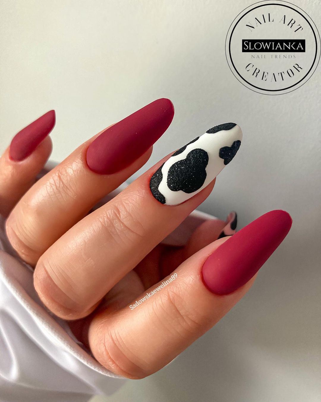 Donkerrode matte nagels met zwart-witte koeienprint