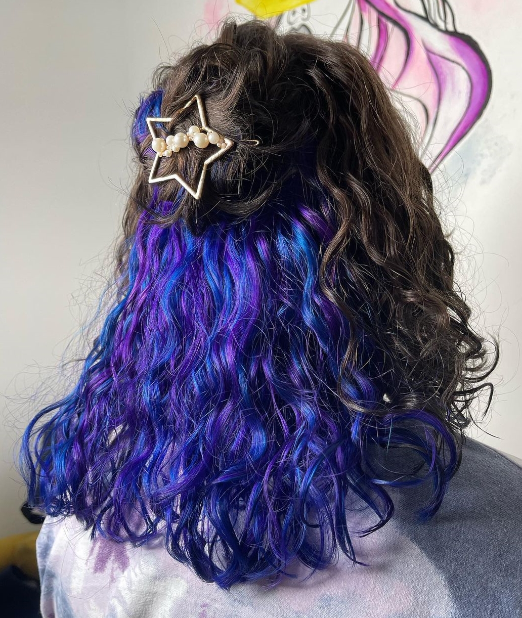 Blauwe en paarse kiekeboe op krullend donker haar