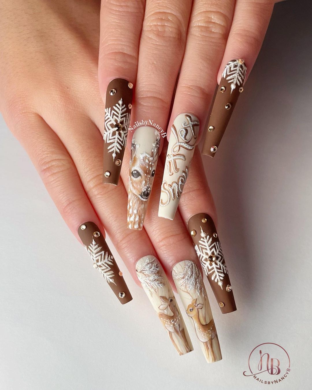 Lange bruine nagels met witte sneeuwvlokken en rendieren