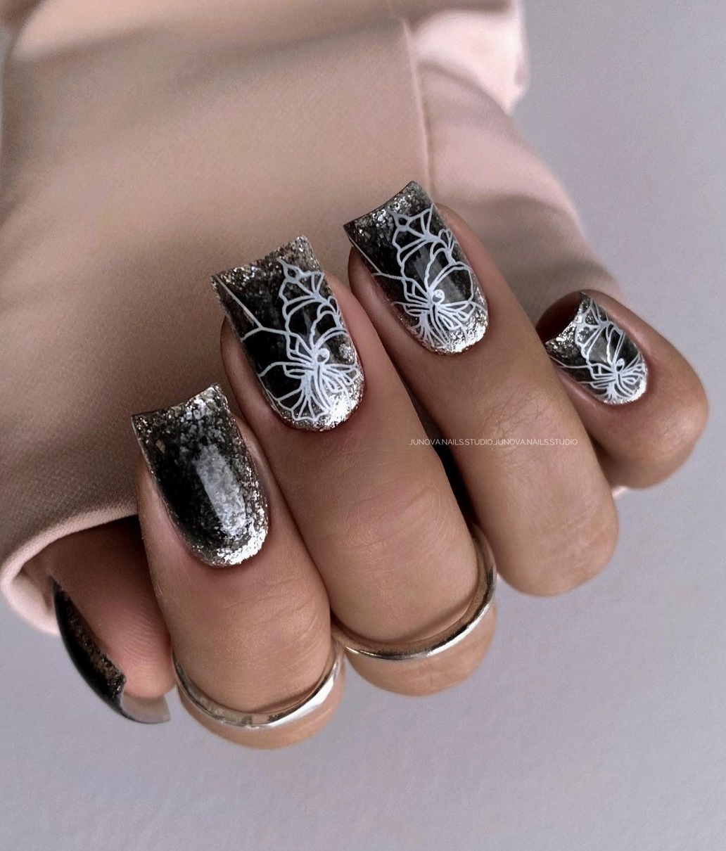 Vierkante zwarte nagels met glitter en wit bloemendessin