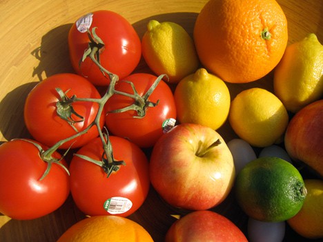 Een kom met fruit zoals tomaten, appels, sinaasappels, citroenen en anderen