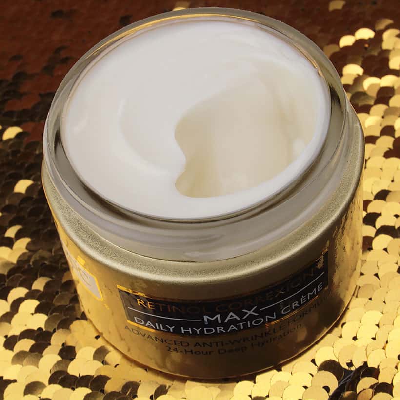 Binnenproduct van RoC Retinol Correxion Max Daily Hydration Crème op een gouden glitterachtergrond met witte kleur crème