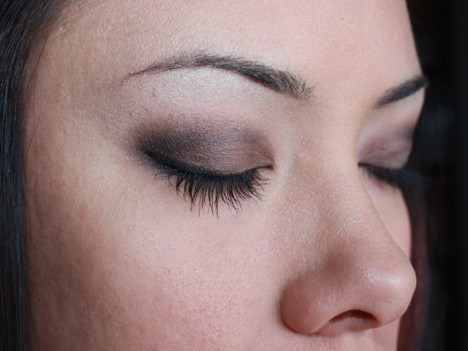 Vrouw in een zijaanzichtpositie die oogschaduw draagt terwijl ze ogen sluit