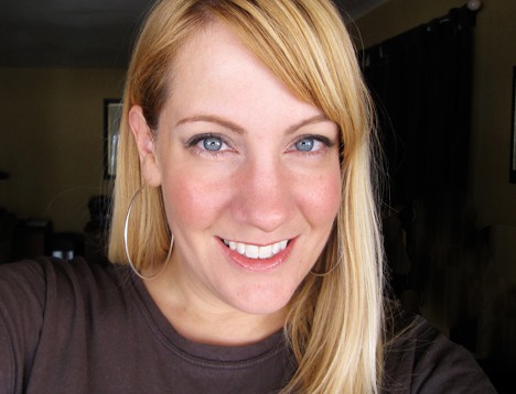 Een blonde vrouw die glimlacht en make-up draagt