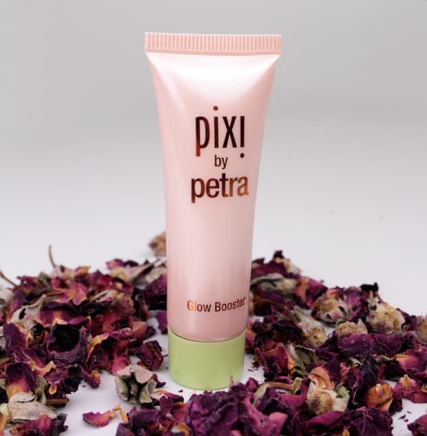 Pixi by Petra Glow Booster product in een paarse rozenblaadjes en lichtblauwe achtergrond