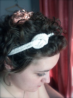 Een vrouw met zwart haar die een wit geknoopte hoofdband draagt