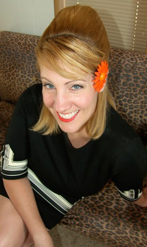 blonde glimlachende vrouw met oranje bloem in haar haar