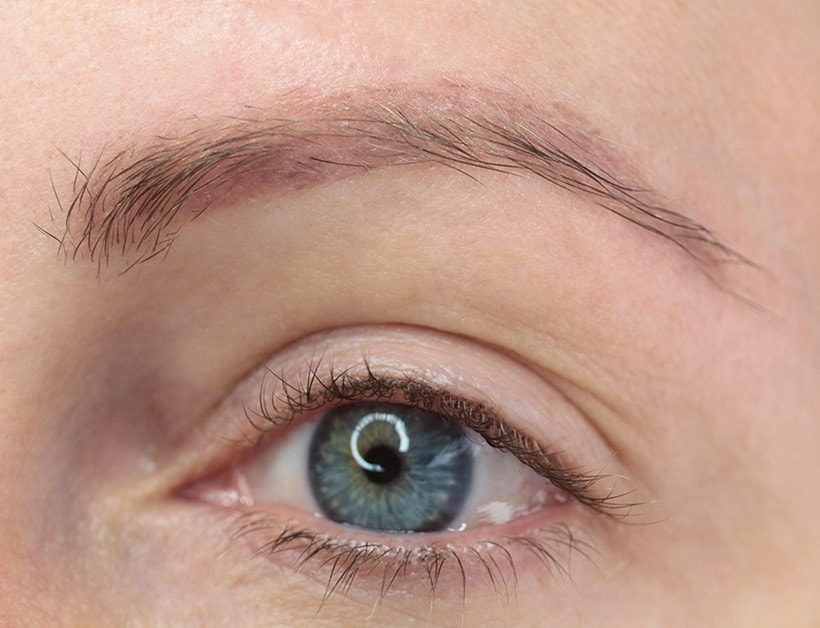 close-up afbeelding van het oog van een vrouw met vervaagde microbladed wenkbrauwen