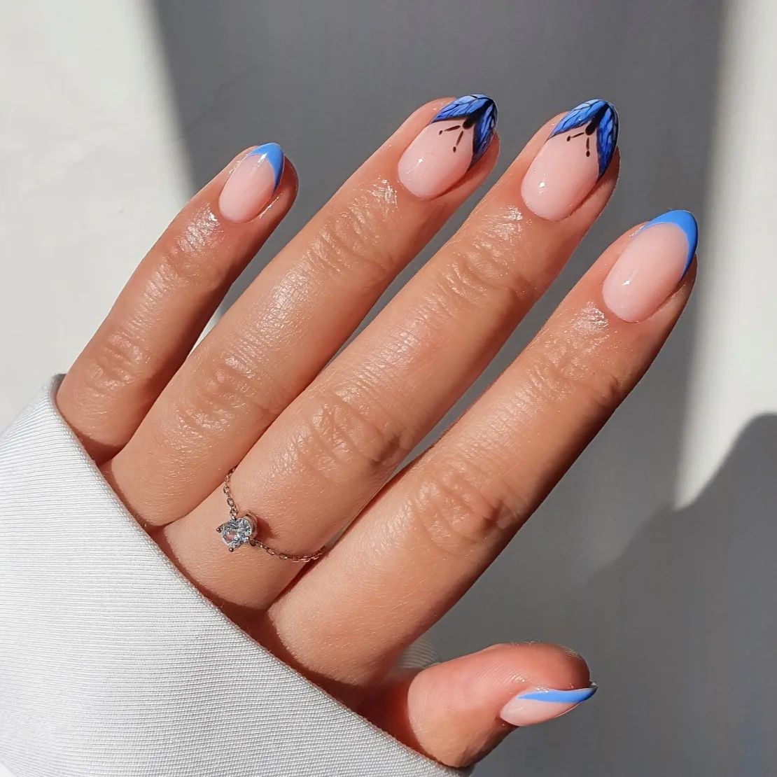 Korte nagels met blauw vlinderontwerp op tips