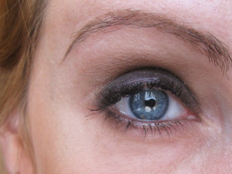 Een close-up van een vrouw met blauwe ogen die grijze oogschaduw draagt