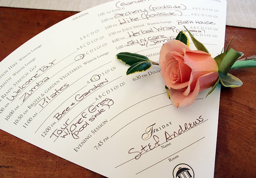 Een waaiervormig papier met lijst van activiteiten met een roos op tafel