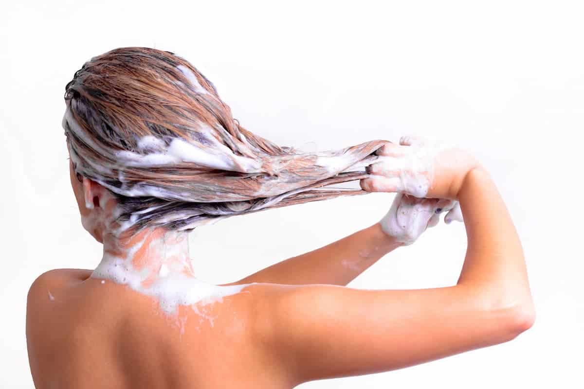 vrouw met lang haar die haar haar wast met shampoo