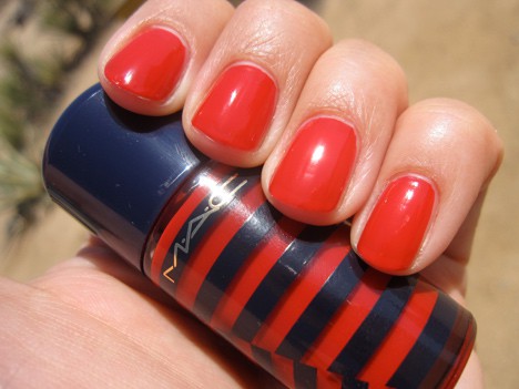 Een hand met een rode nagellak die een vleugje rode nagellak vasthoudt