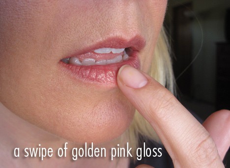 Een close-up afbeelding van de lippen van een vrouw met een veeg van goudroze gloss